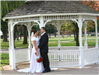 A bride and groom stand in front of a gazebo