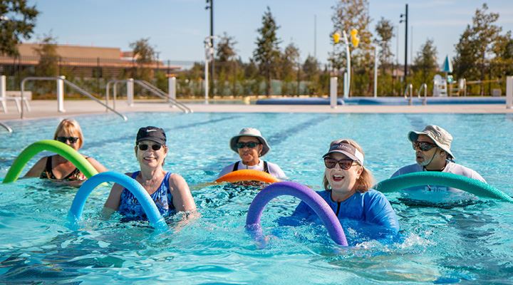 Group of adults in pool doing Swim 'n Stretch.