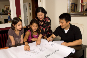 A family looks at a table-sized layout of their home and plans their Fire Escape Plan.