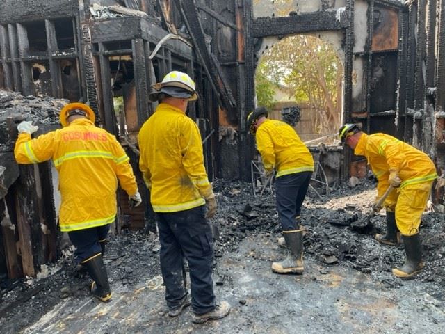 Four investigators examine rubble after a fire