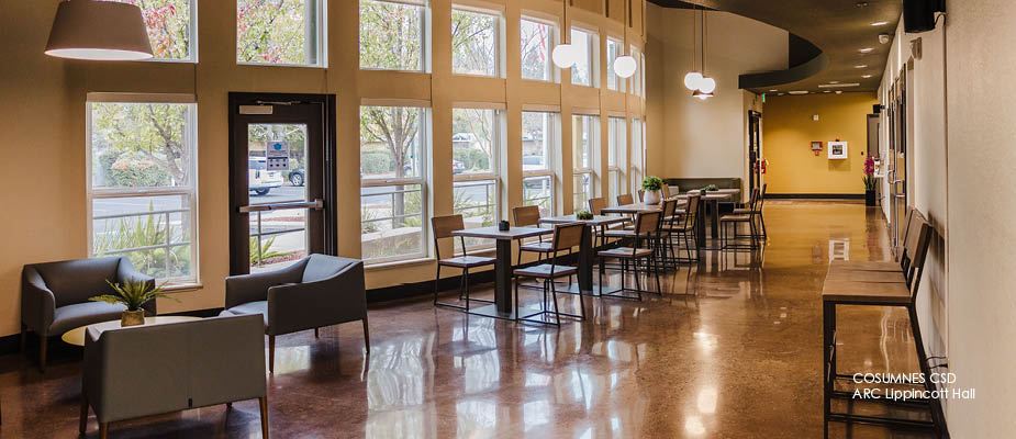 Image of lobby with chairs and tables, lounge chairs and sofa with wall windows.