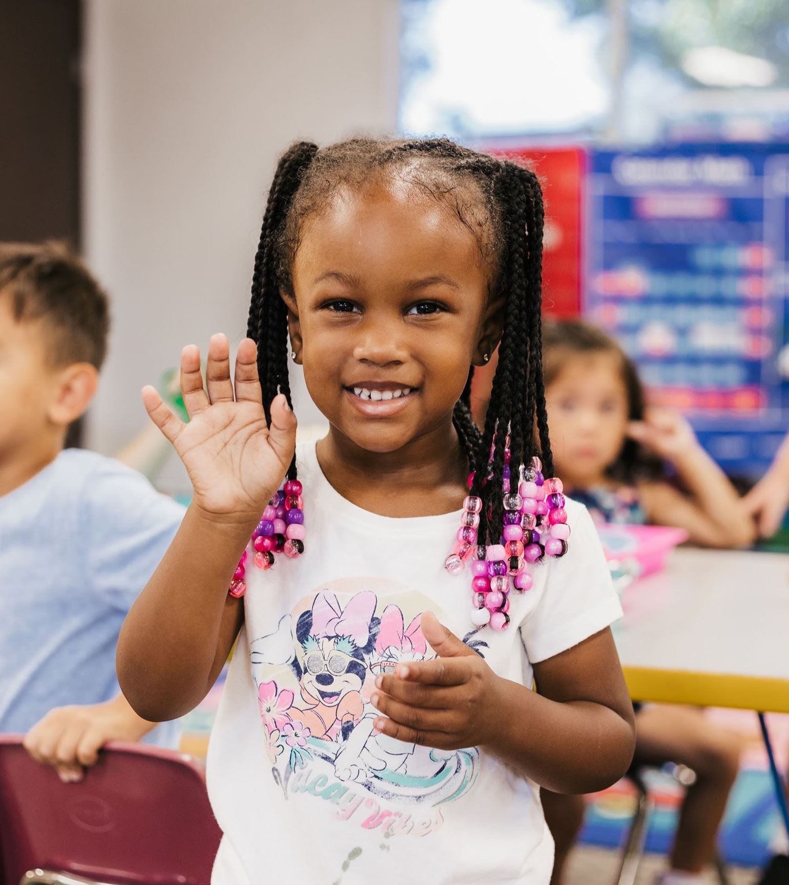 Preschool girl smiling and waving.