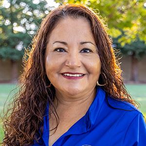A woman with curly brown hair smiles.