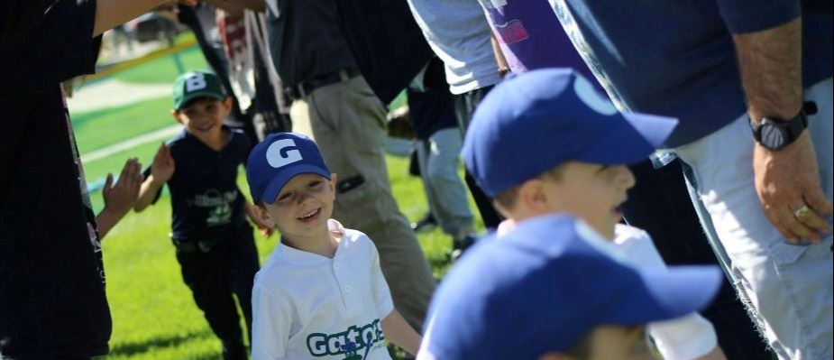T Ball player running through coaches tunnel